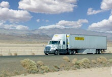A white JB Hunt sleeper cab pulling a white JB Hunt dry van trailer on a highway